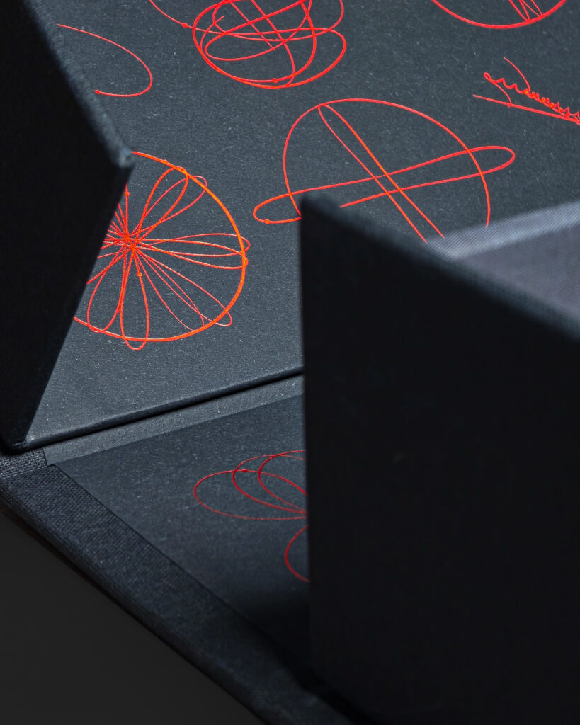 Close-up of the holographic foil three-body pattern inside the clamshell case.